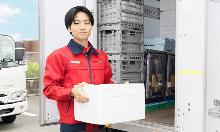 トラックの前で荷物を持つY.K.さん