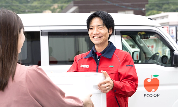 配達先で商品をお客さまに渡すY.K.さん
