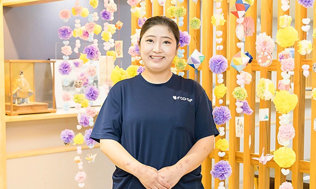 介護施設内の壁の前に立つU.Y.さん
