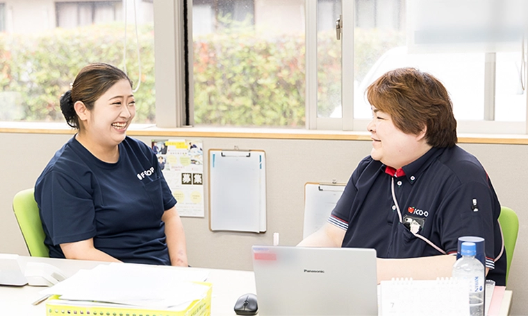 事務所でスタッフ同士が会話する様子